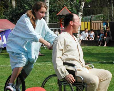 homme en chaise roulante pouss� par une infirmi�re sur un monocycle